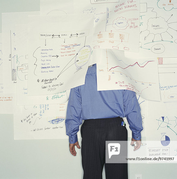 Businessman hiding under drawings on office wall