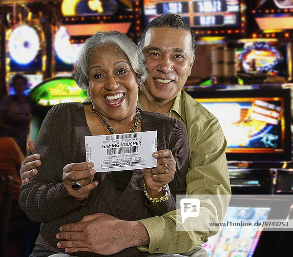 Excited Black couple holding gaming voucher in casino