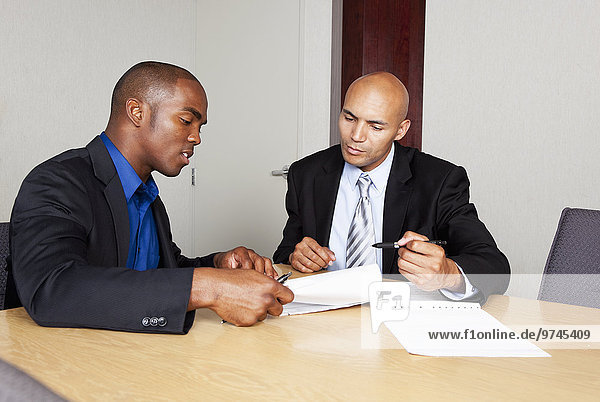 Mixed race businessmen reviewing contract in conference room