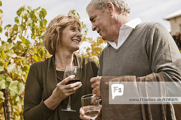 Caucasian couple drinking wine in vineyard