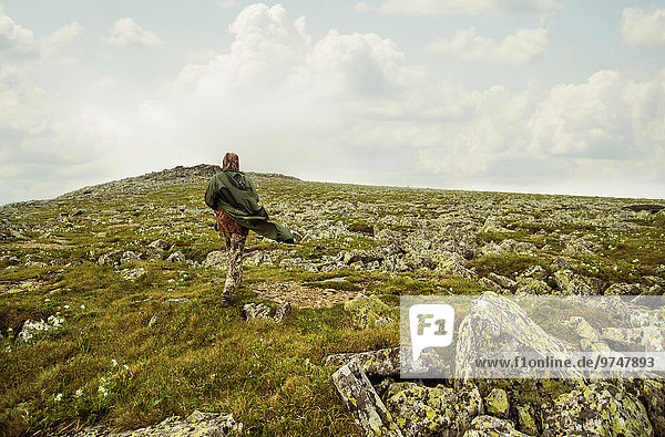 Caucasian hiker walking on rocky hillside