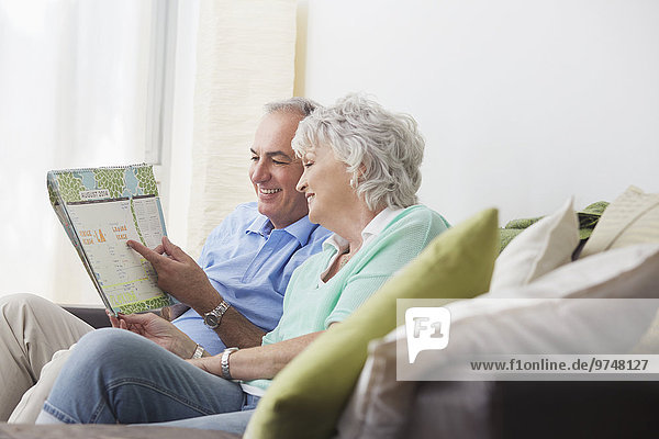 Older couple reading paperwork on sofa