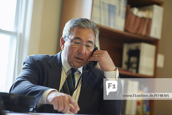 Mixed race businessman talking on telephone in office
