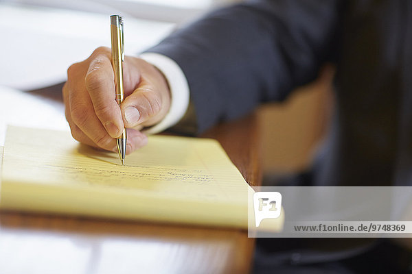 Mixed race businessman writing on notepad at desk