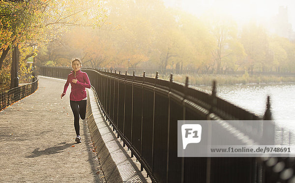 Asian woman running on waterfront path