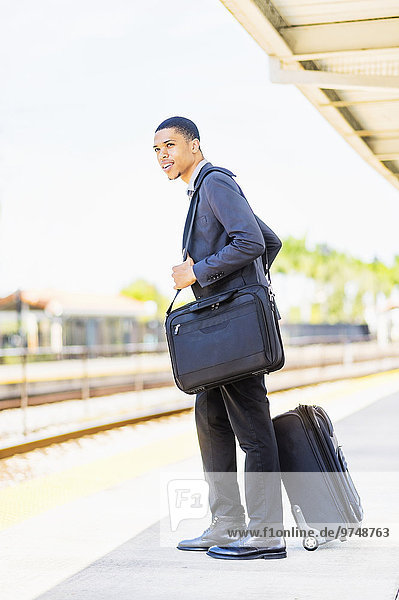 Black businessman waiting on train platform