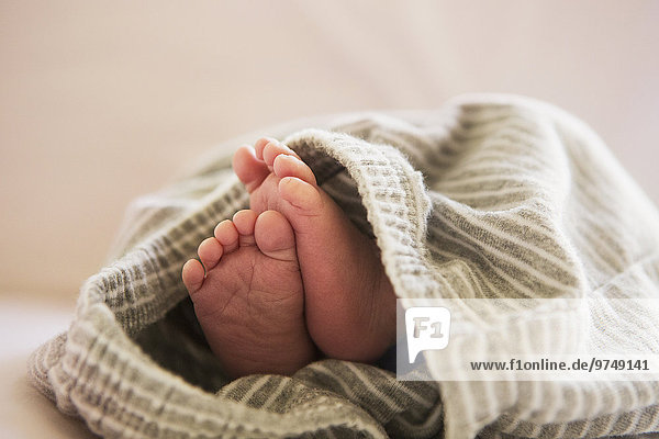 Close up of feet of mixed race baby in blanket