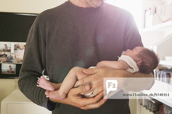Father holding newborn baby in bedroom