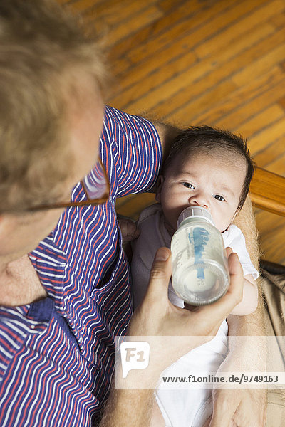 High angle view of father bottle feeding baby