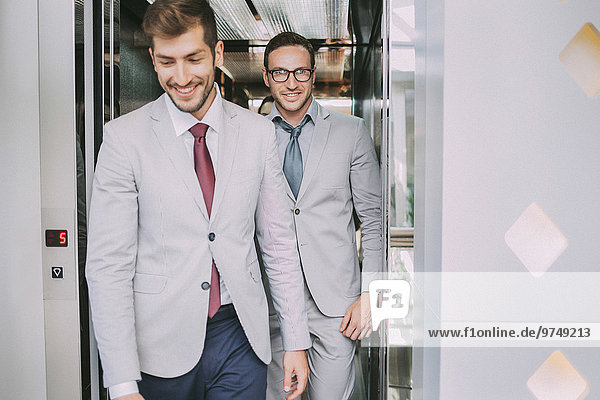 Caucasian businessmen walking out of elevator