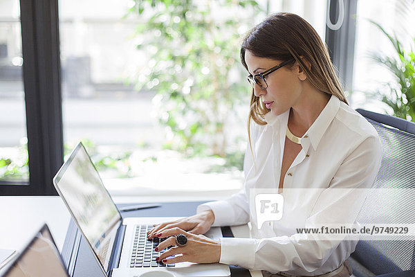 Caucasian businesswoman working at laptop at desk