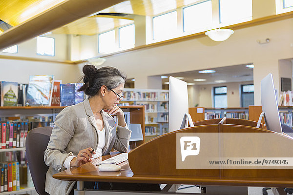 Older Caucasian woman using computer in library