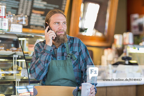 Caucasian server talking on telephone in cafe