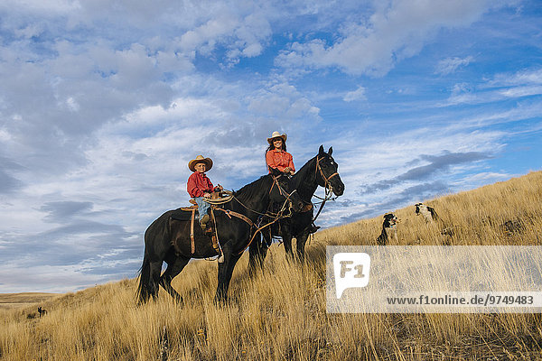 Caucasian mother and son on horseback on grassy hill