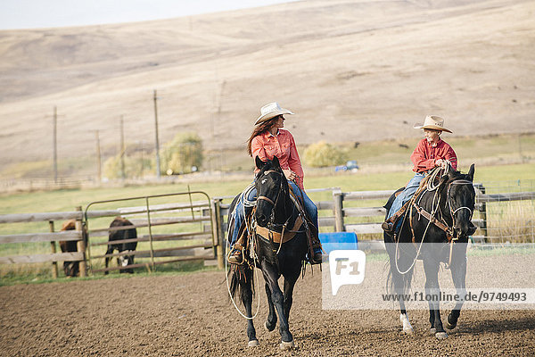 Caucasian mother and son riding horses on ranch