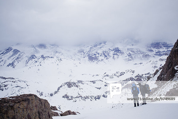 Hispanic hikers admiring snowy scenic mountains