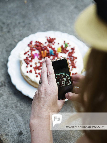 Woman taking picture of cake with her cell phone