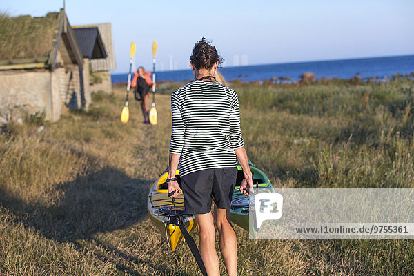 Woman carrying kayaks  rear view