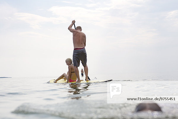 Man with teenage daughter on paddle board