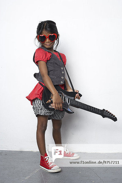 Mädchen mit Spielzeuggitarre mit roter herzförmiger Sonnenbrille
