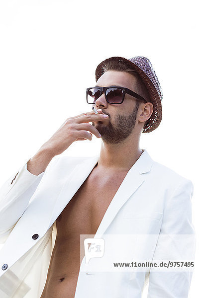 Smoking young man wearing hat  sunglasses and white jacket on bare chest