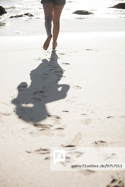 Legs of young woman running on beach