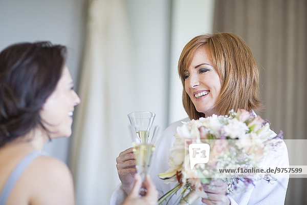 Braut und Brautjungfer klirrende Champagnergläser bei der Hochzeitsvorbereitung