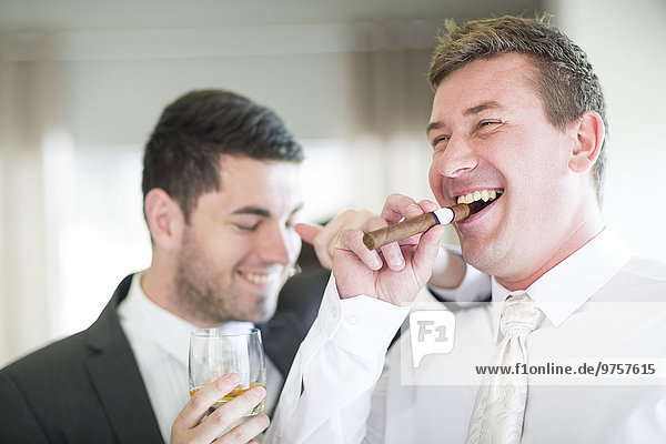 Bräutigam Rauchen einer Zigarre mit Trauzeugen vor der Hochzeit