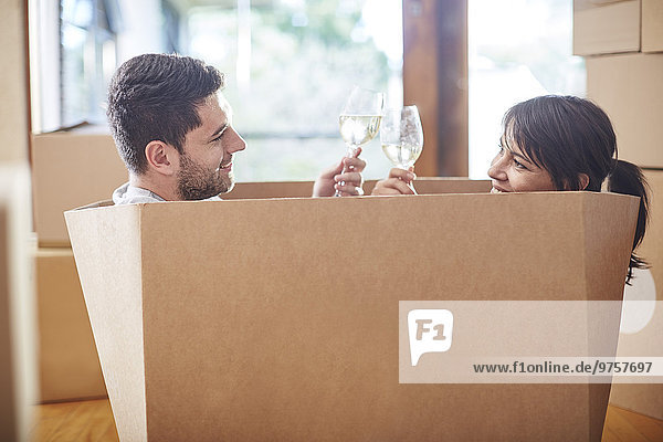 Paar Umzug in einer Kiste sitzend und klirrende Weingläser