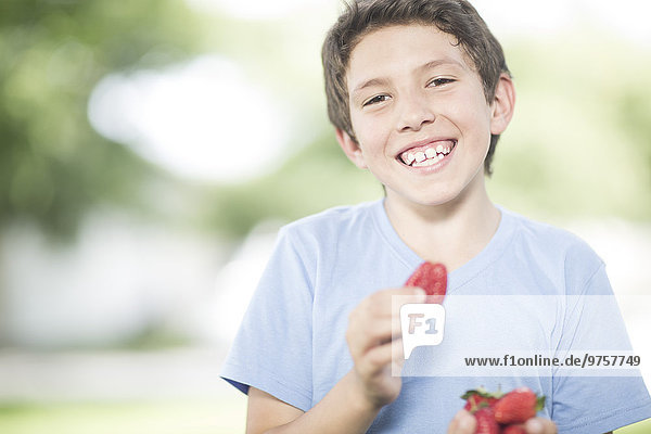 Porträt eines lächelnden Jungen mit Erdbeeren