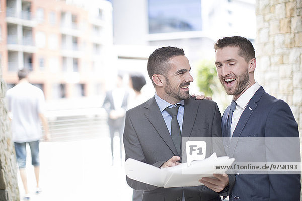 Happy gay couple with business suits looking at papers