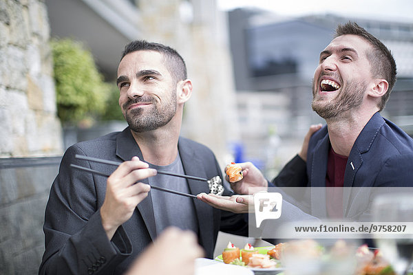 Schwules Paar beim Sushi-Essen im Außenrestaurant