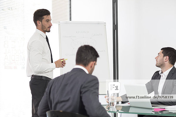 Businessman in boardroom leading a meeting with flip chart