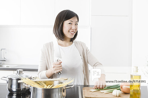 Porträt einer lächelnden jungen Frau beim Kochen