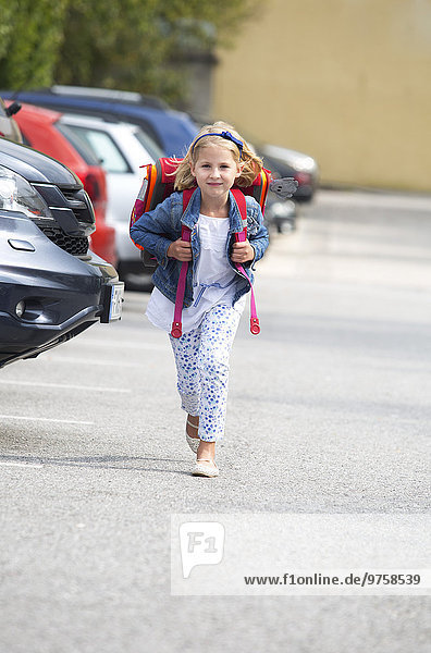 Kleines Mädchen auf dem Schulweg über den Parkplatz