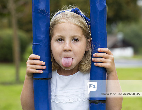 Porträt eines kleinen Mädchens,  das seine Zunge herausstreckt.