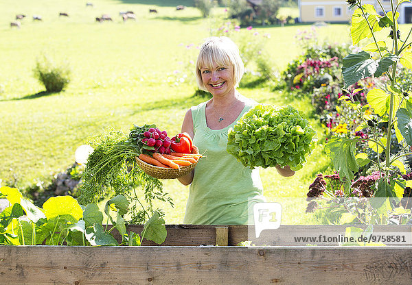 Österreich  Mondsee  Porträt der glücklichen Frau mit ihrer Gemüseernte