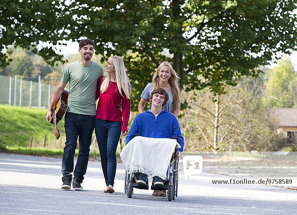 Junger Mann im Rollstuhl mit Freunden