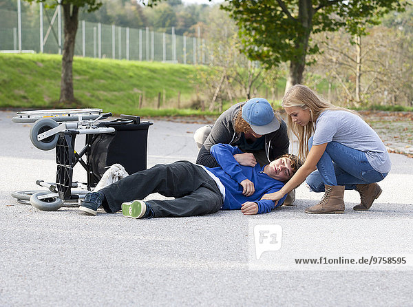 Two young people assisting young wheelchair user after fall