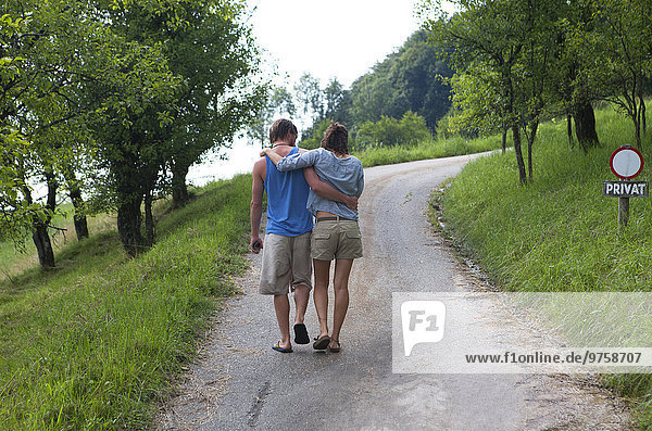 Couple walking arm in arm on a private road