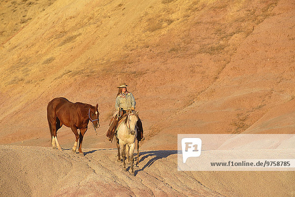 USA  Wyoming  Cowgirl mit zwei Pferden in Badlands