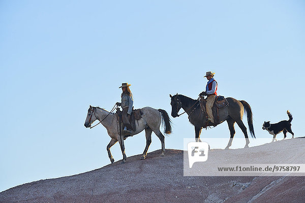 USA  Wyoming  zwei reitende Cowgirls und Theit Dog in Badlands