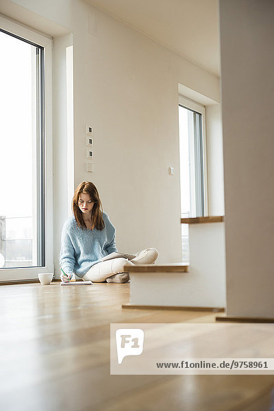 Young woman sitting on floor taking notes