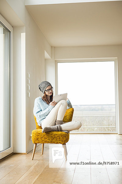 Junge Frau sitzt auf einem Stuhl mit einem digitalen Tablett