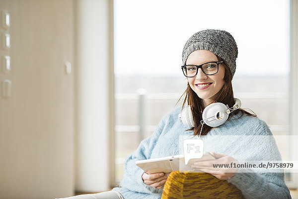 Lächelnde junge Frau mit digitalem Tablett und Kopfhörer