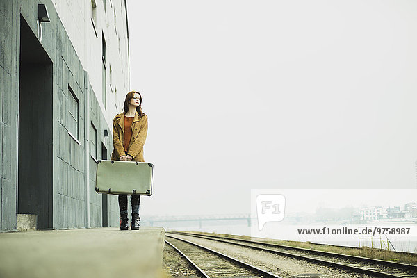 Junge Frau mit Koffer auf Plattform