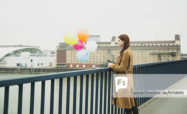 Junge Frau auf der Brücke mit einem Haufen Luftballons