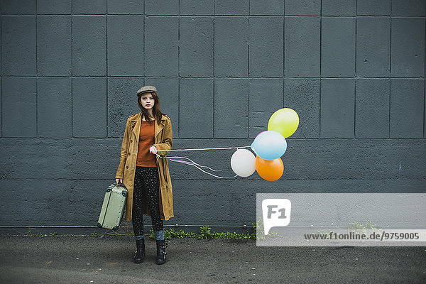 Junge Frau mit Koffer mit Ballonhülle