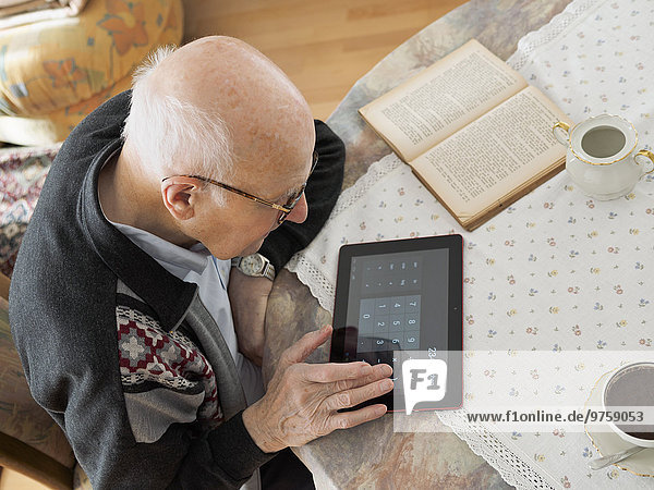 Alter Mann am Tisch sitzend mit digitalem Tablett