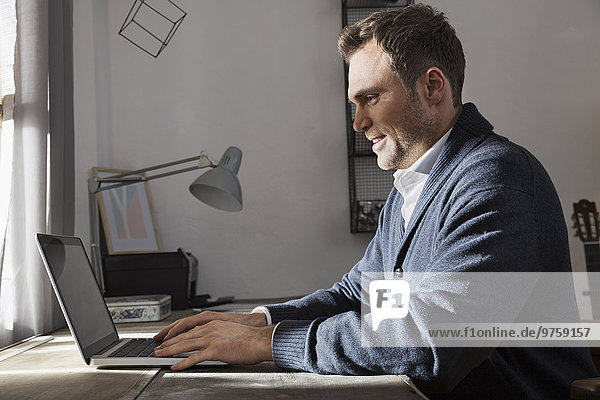 Mann arbeitet mit Laptop zu Hause